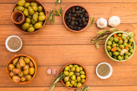Still life with different varieties of olives, presented in bowls on wooden boards, seasoned with different traditional dressings. Traditional homemade dressings, typical of Mediterranean cuisine.の写真素材