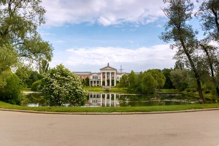 The building is of pink brick with white columns on the shore of the pond. Laboratory building of the Main Botanical garden of Russian Academy of Sciences, Moscow. Summer. Morning. Cloudy.のeditorial素材