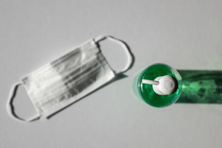 medical mask and disinfectant gel on white background inside a house