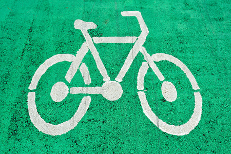 White bicycle sign painted on an green asphalt road.の写真素材