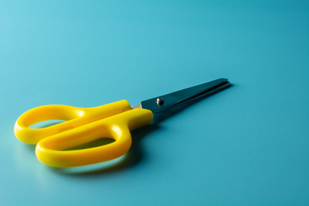 yellow plastic scissors on blue paper. - backgroundの写真素材