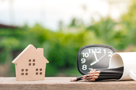 brown wooden home icon on wood desk in the morning. For real estate background.