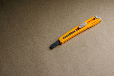 yellow cutter on brown recycled paper - backgroundの写真素材