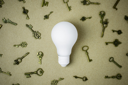 white light bulb and many keys on brown paper backgroundの写真素材