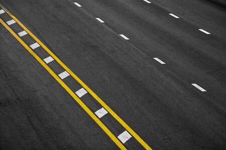 Yellow and white paint line on black asphalt. space transportation background