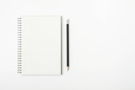 grid paper book and pencil on a white desk - for business concept background