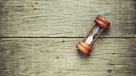 classic hourglass on old wood background. - vintage backdrop style.