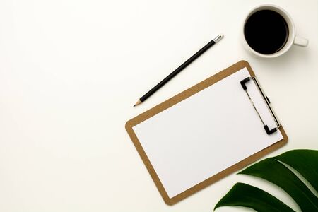clipboard and white paper on white office desk background. Flat lay design.