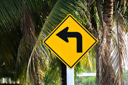 Yellow road sign - turn left in the countrysideの写真素材