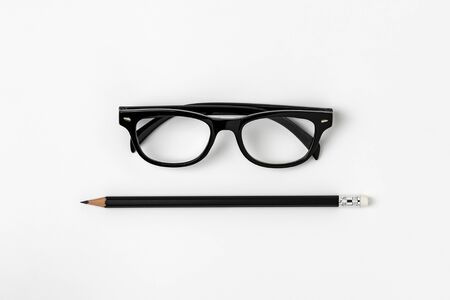 glasses and a black pencil on white backgroundの写真素材