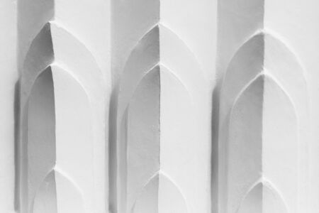 line of low relief sculpture at white concrete wall with shadow.の写真素材