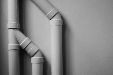 white plastic pipe at white cement wall with shadow.の写真素材