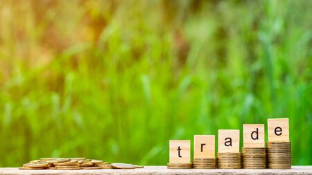 trade word on stack of coins and a pile of golden coins on wooden table.の写真素材