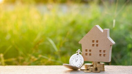 small house model and a clock with golden coins pile. - saving and investment for future planning concept.の写真素材