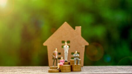 Miniature businessman figure sit on a golden coins and a small home model. - Finance and house loan, saving money for a car concepts.の写真素材