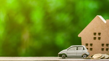 Grey miniature car model and coins on wooden table. - Finance and car loan, saving money for a car concepts.の写真素材