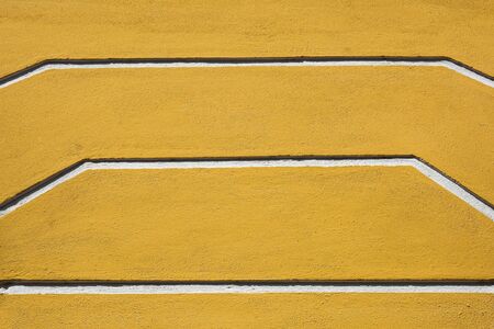 line of low relief sculpture at yellow concrete wallの写真素材
