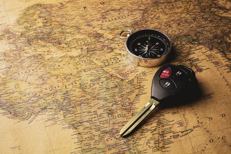 Modern electronic car keys and compass on vintage map .の写真素材
