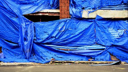 damage and old blue canvas cover at construction site.の写真素材