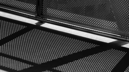 light and shadow of wire mesh on pavement - monochromeの写真素材