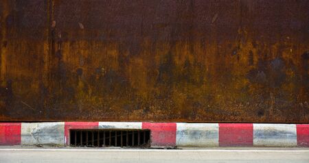 drainage hole at the curb of red-white sidewalk - road in the cityの写真素材