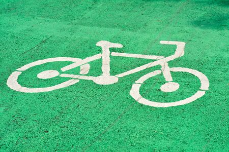 White bicycle sign painted on an green asphalt road in the park