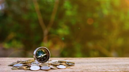 compass on pile of a golden coins at old wooden table. - direction of business and management...