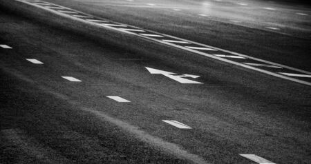 white arrow go straight and turn right sign on black asphalt. space transportation backgroundの写真素材