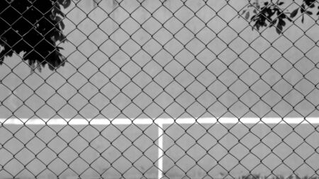 cage metal wire front the tennis court and wall for practice - monochrome