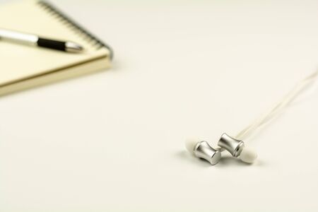 earphone with diary book and pen on white desk background.の写真素材