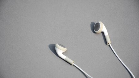 white earphones on grey background - using digital music or smartphone.の写真素材