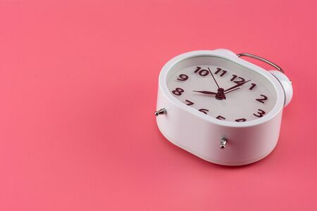 white alarm clock on pink background.の写真素材