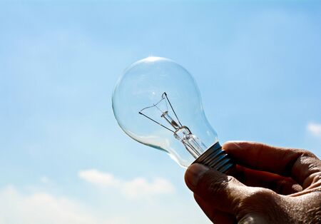 Ceiling lamp in hand on blue sky backgroundの写真素材