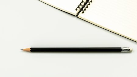 diary book and a pencil on white desk background with copy space. - top view.の写真素材