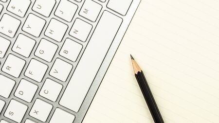 modern white office desk with a computer keyboard, pen, and a notebook. - top view with copy space.の写真素材