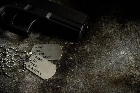 Blank military dog tags and a gun on abandoned rusty metal plate. - Memories and sacrifices concept.の写真素材