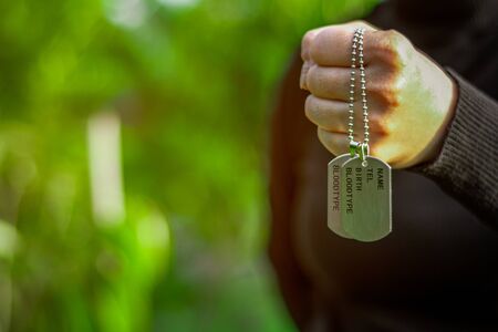 Women's is holding blank military dog tags in hand. - Memories and sacrifices concept.の写真素材