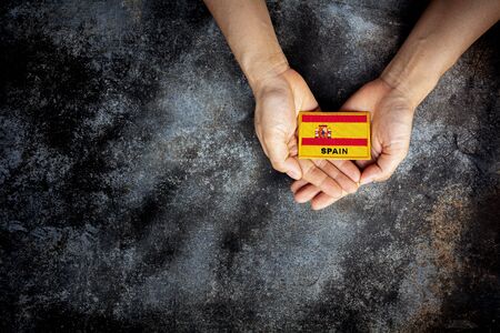 Small Spain flag in a hand. - Love, care, protect and safe concept.