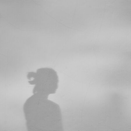 Shadow of a girl on a white concrete wallの写真素材