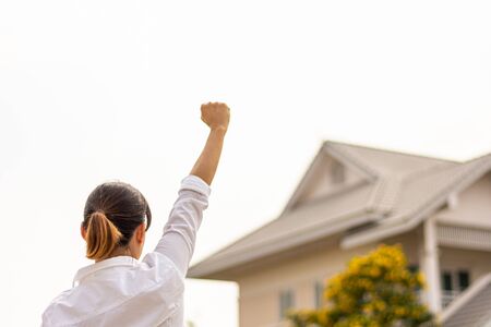 woman raise hands to show success front a home. - buy house and real estate concept.の写真素材