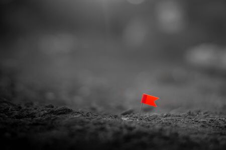 red push pin flag marking a location on the arid ground.の写真素材