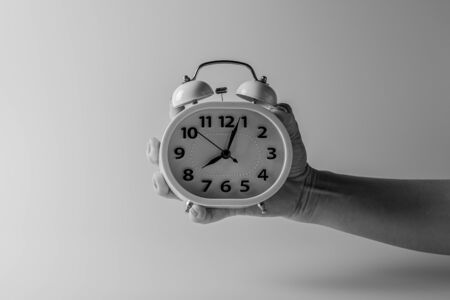 Hand holding a white alarm clock. - thinking and control timing ideas concept.の写真素材