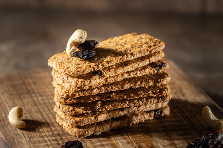 Whole grain oat cookies, biscuit crackers with nut kernels and raisins, wooden background. High...