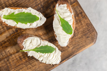Sandwiches with curd cream cheese on wooden board background. Space for text.の写真素材