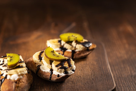Kiwi and banana sweet sandwiched with chocolate sauce on wooden background. High quality photoの写真素材
