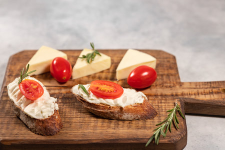 Cream cheese sandwiches with tomato and rosemary on brown wooden board, free space for text. High quality photoの写真素材