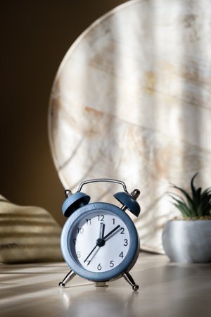 Blue alarm clock on table on wooden background with natural shadows, new day beginning concept, verticalの写真素材
