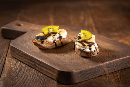 Sweet sandwiches with yogurt, banana and kiwi, Handmade fruit bruschetta with chocolate syrup, free space for textの写真素材