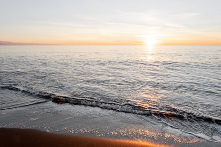 Beach Sunset, Black magnetite sand and sea waves, copper highlights on sand, blurred background with selective focusの写真素材