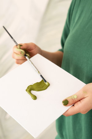 Hand holding brush paper with green paint, creating artの写真素材